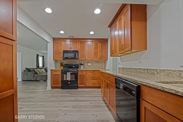 a kitchen with stainless steel appliances granite countertop wooden cabinets a stove top oven a sink and dishwasher with wooden floor