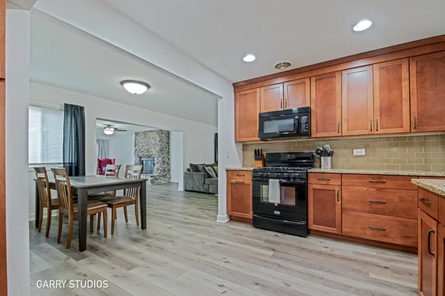 a view of a livingroom with a fireplace a ceiling fan and wooden floor
