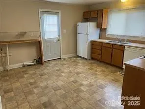 a view of kitchen with refrigerator cabinets and a sink