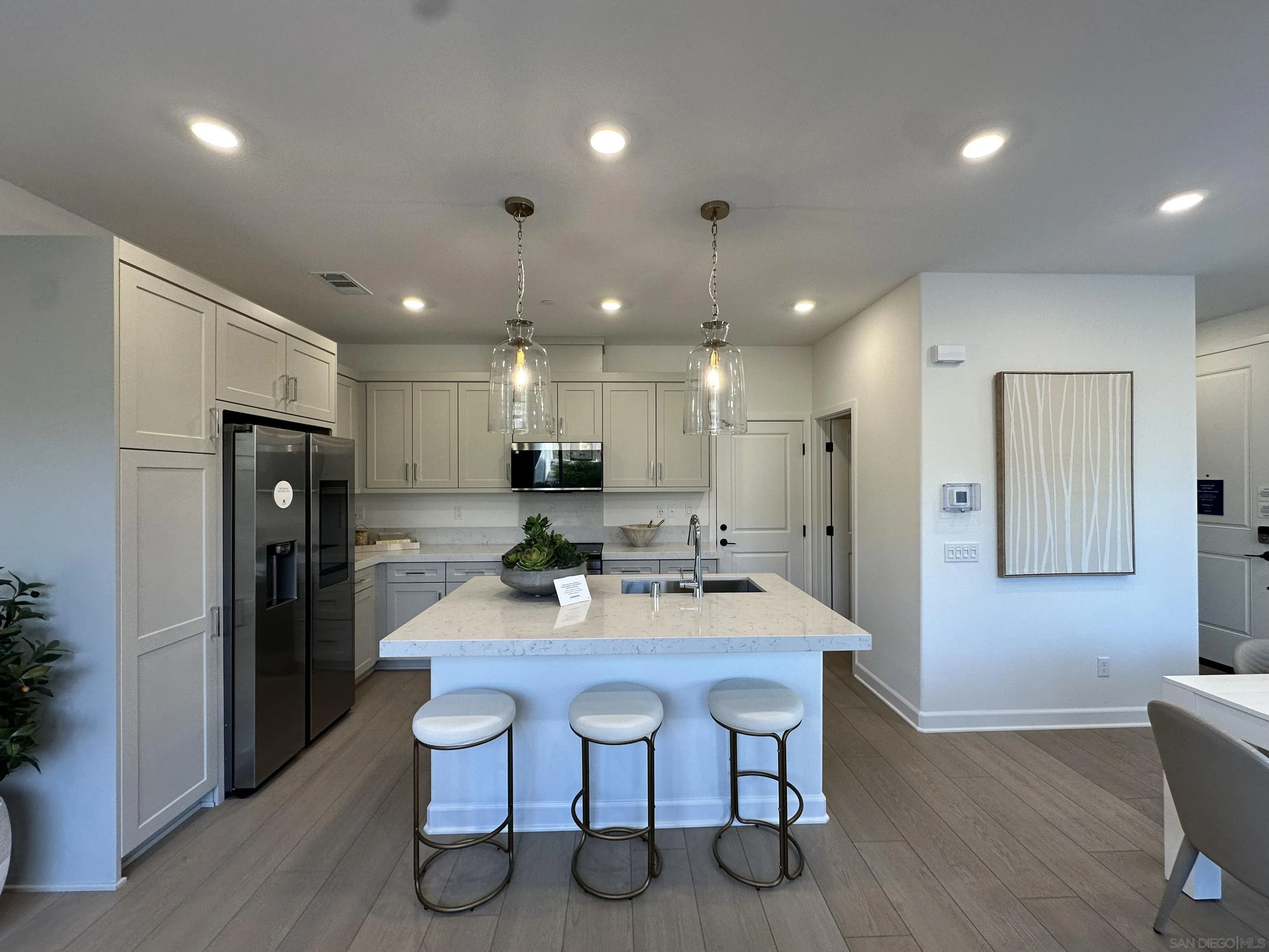 2186 Tributary Drive Chula Vista, CA 91913 - Photo 7 of 30 a kitchen with stainless steel appliances kitchen island granite countertop a dining table chairs refrigerator and microwave