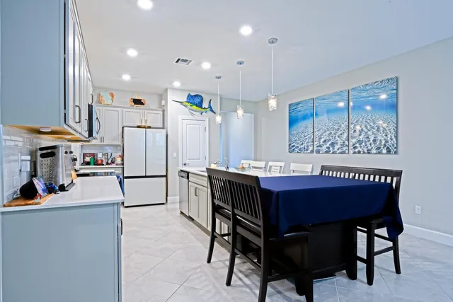 a kitchen with a dining table chairs refrigerator and cabinets