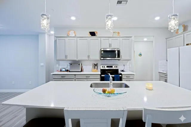a kitchen with a white cabinets appliances and a dining table