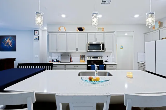 a kitchen with stainless steel appliances a white table chairs and a refrigerator