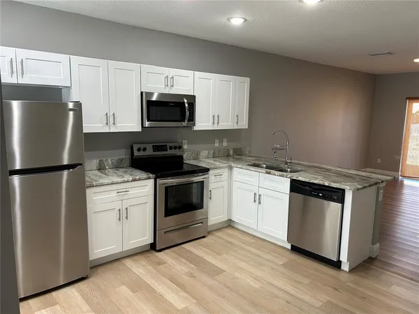a kitchen with white cabinets stainless steel appliances and a sink