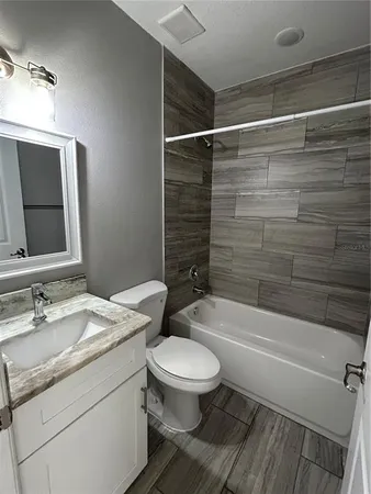 a bathroom with a granite countertop bathtub shower sink mirror vanity and toilet