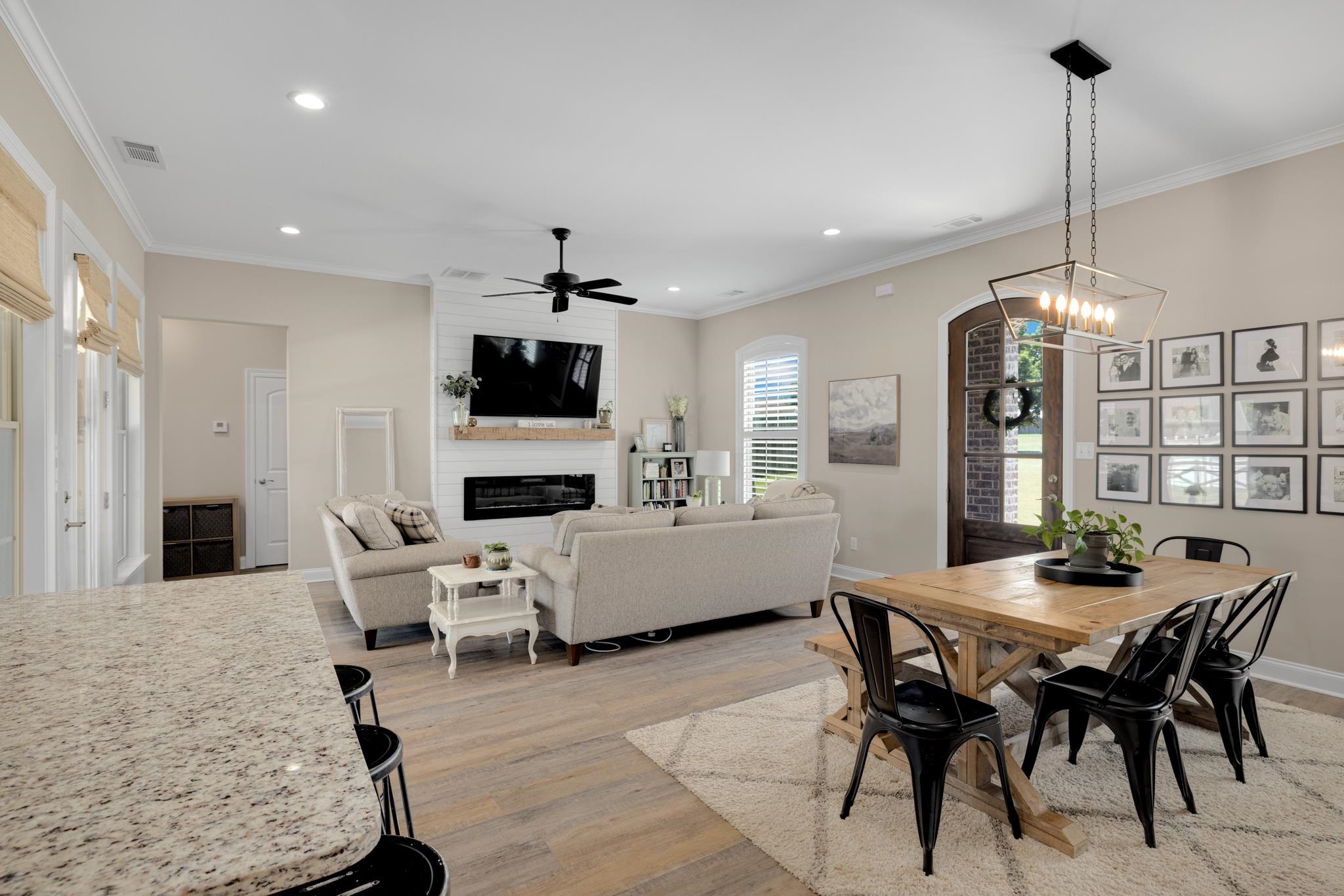 410 Rosemark Road Atoka, TN 38004 - Photo 4 of 30 Dining space featuring a large fireplace, hardwood / laminate flooring, crown molding, and ceiling fan