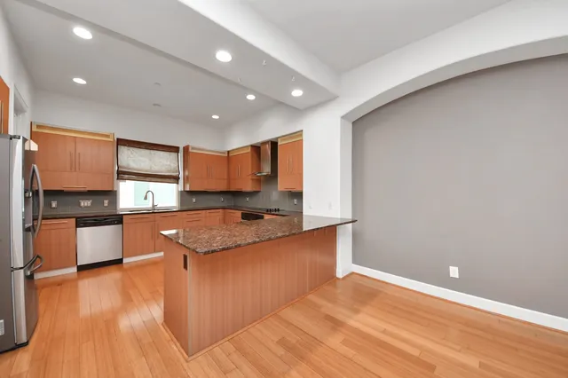 a large kitchen with stainless steel appliances granite countertop a large counter top a sink and a stove