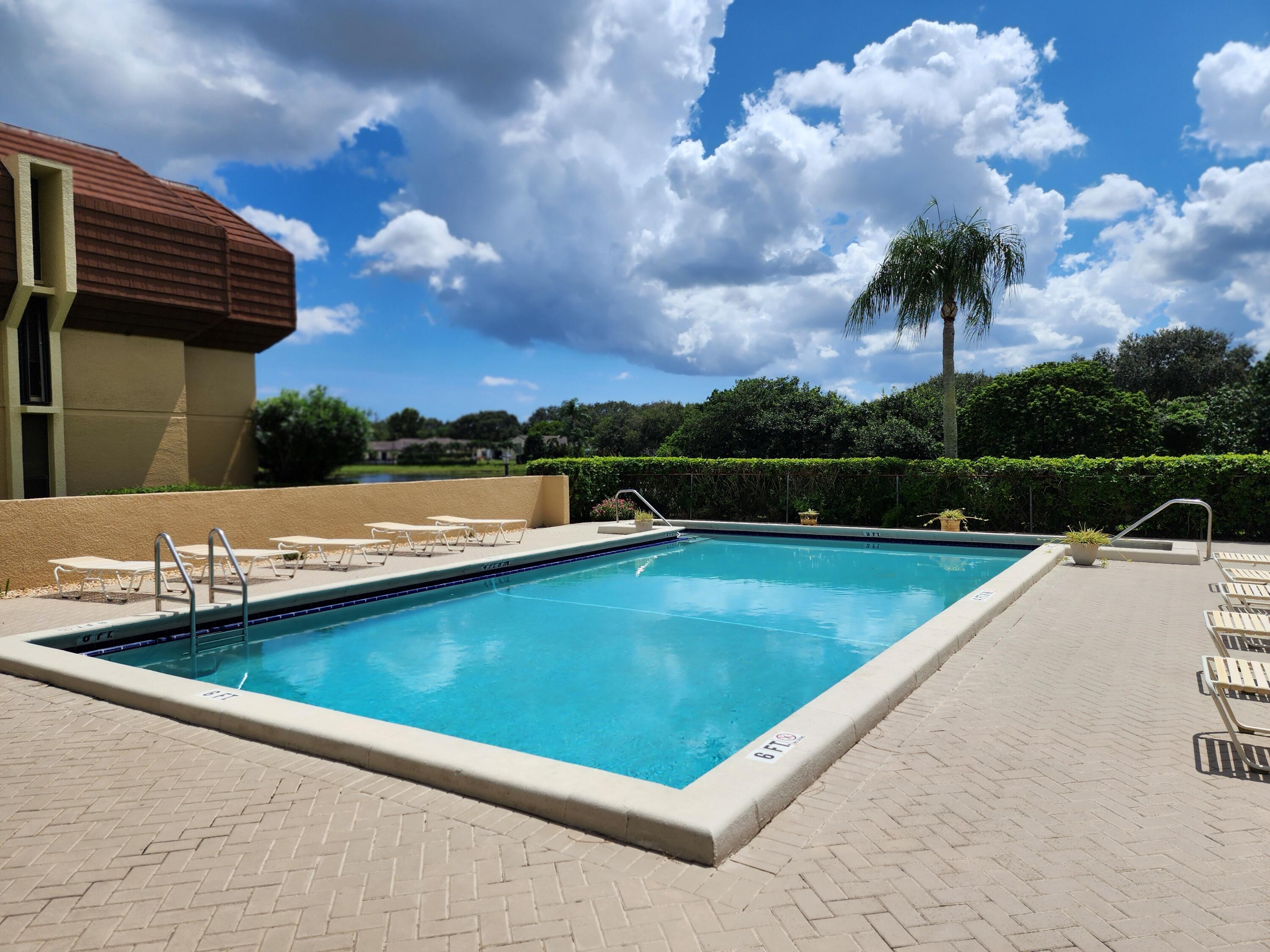 5344 Woodland Lakes Drive, Unit 223 Palm Beach Gardens, FL 33418 - Photo 41 of 46 a view of a swimming pool and lounge chairs