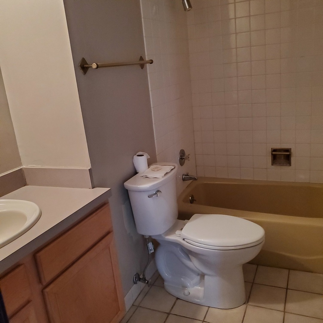 9242 Gross Point Road, Unit 107 Skokie, IL 60077 - Photo 7 of 13 a white toilet sitting next to a bathroom sink and vanity
