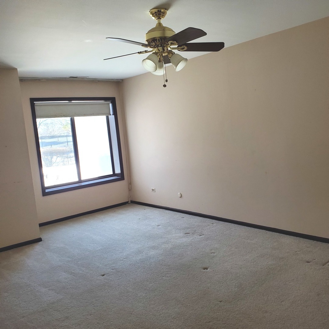 9242 Gross Point Road, Unit 107 Skokie, IL 60077 - Photo 8 of 13 an empty room with a window and a chandelier fan