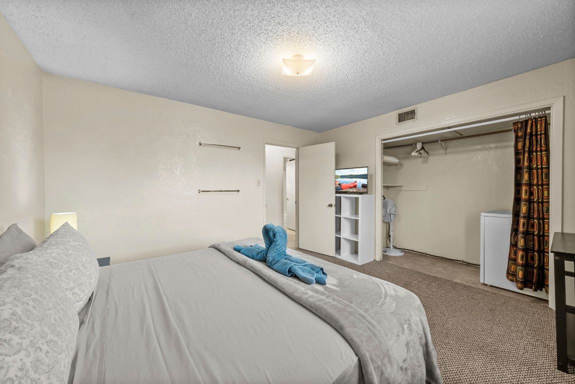 202 West Wheeler Street Manor, TX 78653 - Photo 14 of 28 a bedroom with a large bed and a chandelier