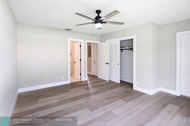 an empty room with wooden floor and ceiling fan