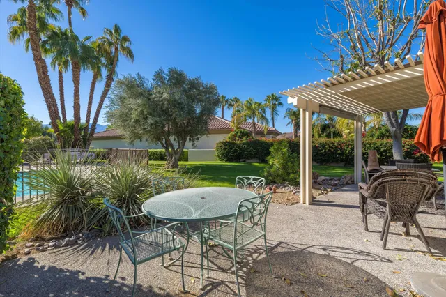 a view of a patio with table and chairs potted plants and palm tree