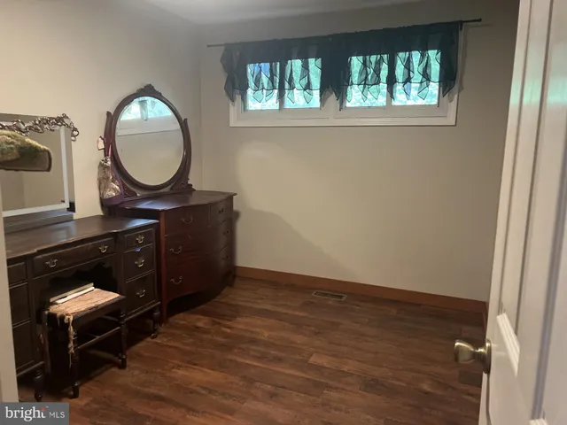 a living room with a mirror and a wooden floor