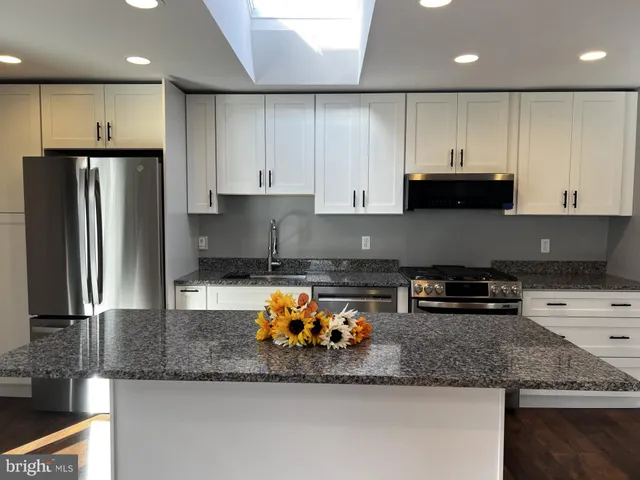 a kitchen with stainless steel appliances granite countertop a refrigerator sink and cabinets