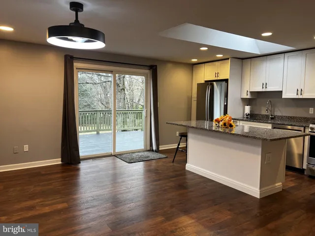 a kitchen with stainless steel appliances granite countertop a stove a refrigerator a sink with wooden cabinets and wooden floor