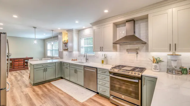 a view of a kitchen with kitchen island a sink dishwasher a dining table and chairs with wooden floor