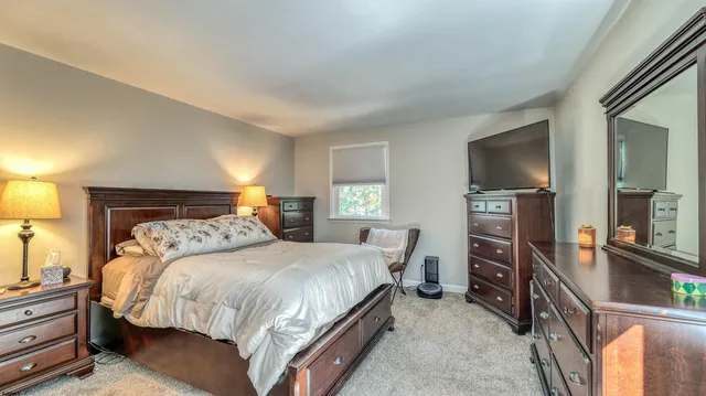 a bedroom with a large bed and a dresser with mirror