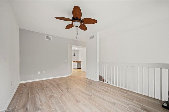 a view of a room with wooden floor fan and windows