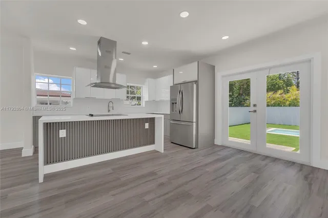 a kitchen with stainless steel appliances granite countertop a refrigerator a sink a stove a microwave and wooden floors