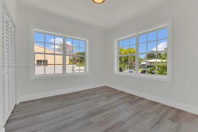a view of an empty room with window and wooden floor