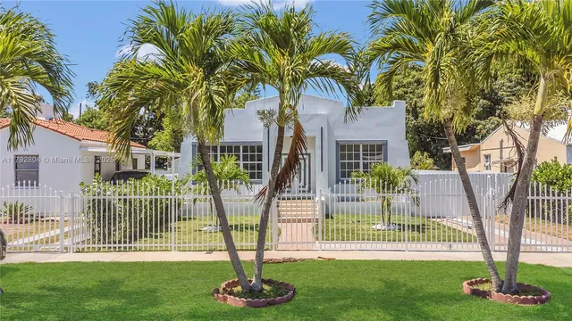 a front view of a house with a yard and palm trees