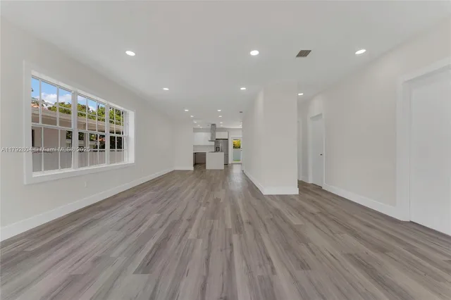 a view of empty room with wooden floor and windows