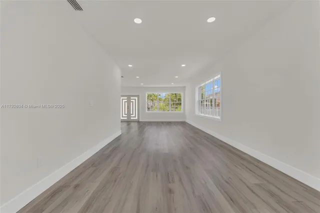 a view of an empty room with window and wooden floor