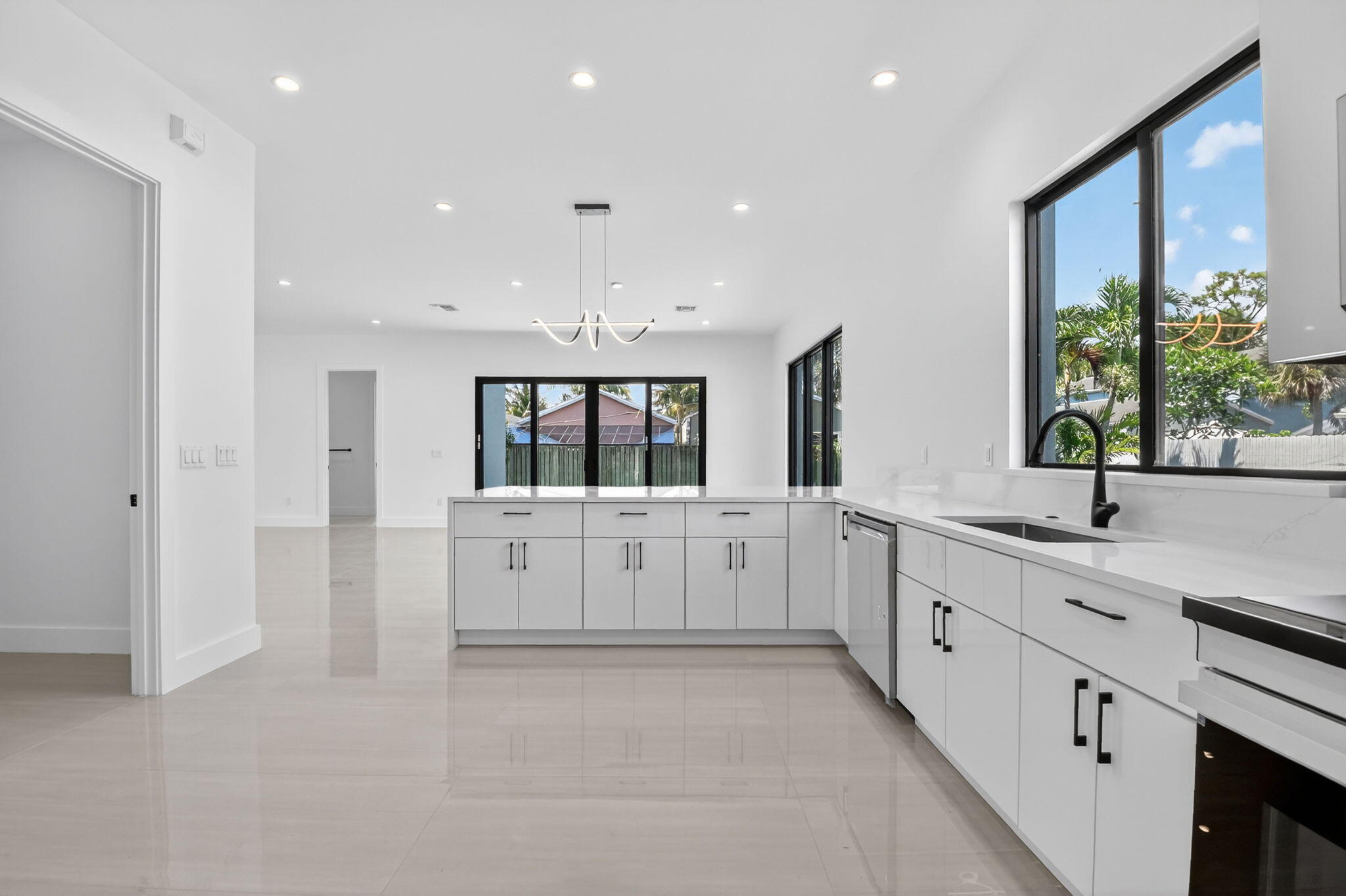 3920 Espan Court Palm Springs, FL 33461 - Photo 17 of 51 a large white kitchen with center island and stainless steel appliances