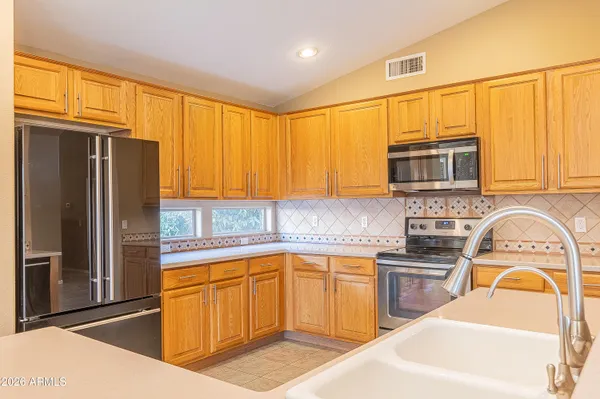 a kitchen with stainless steel appliances granite countertop a refrigerator a sink dishwasher stove top oven and cabinets
