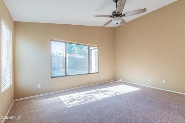 an empty room with windows and fan