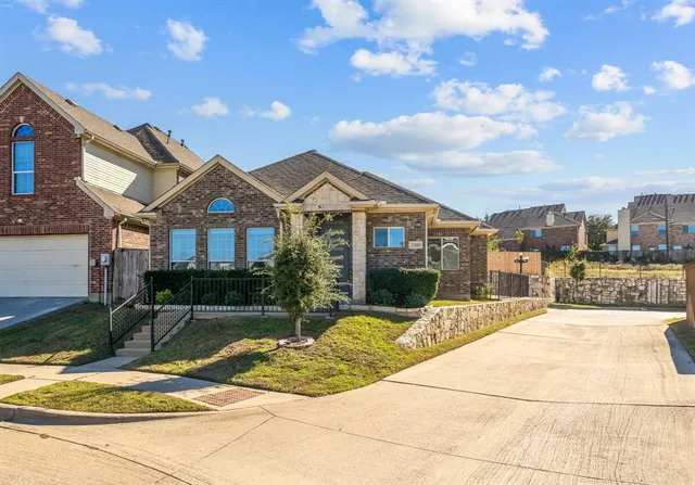 a view of a white house with a large tree and plants