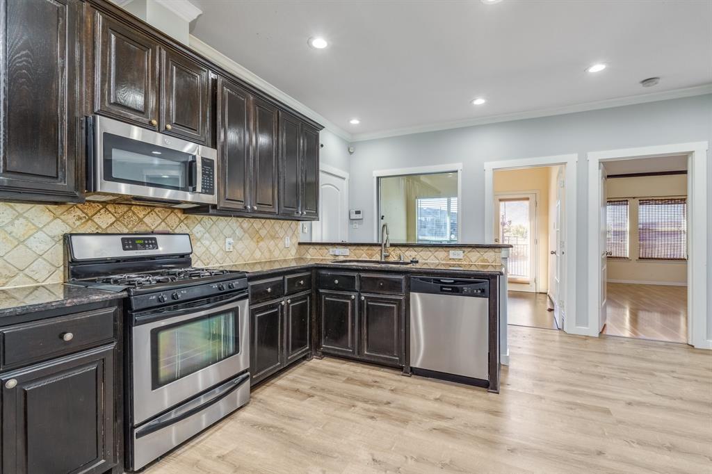 2300 Janna Way Carrollton, TX 75006 - Photo 21 of 40 a kitchen with stainless steel appliances granite countertop wooden cabinets stove top oven and sink