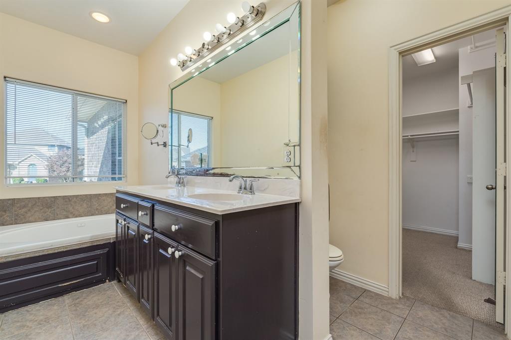2300 Janna Way Carrollton, TX 75006 - Photo 30 of 40 a bathroom with a sink a large mirror and a bathtub