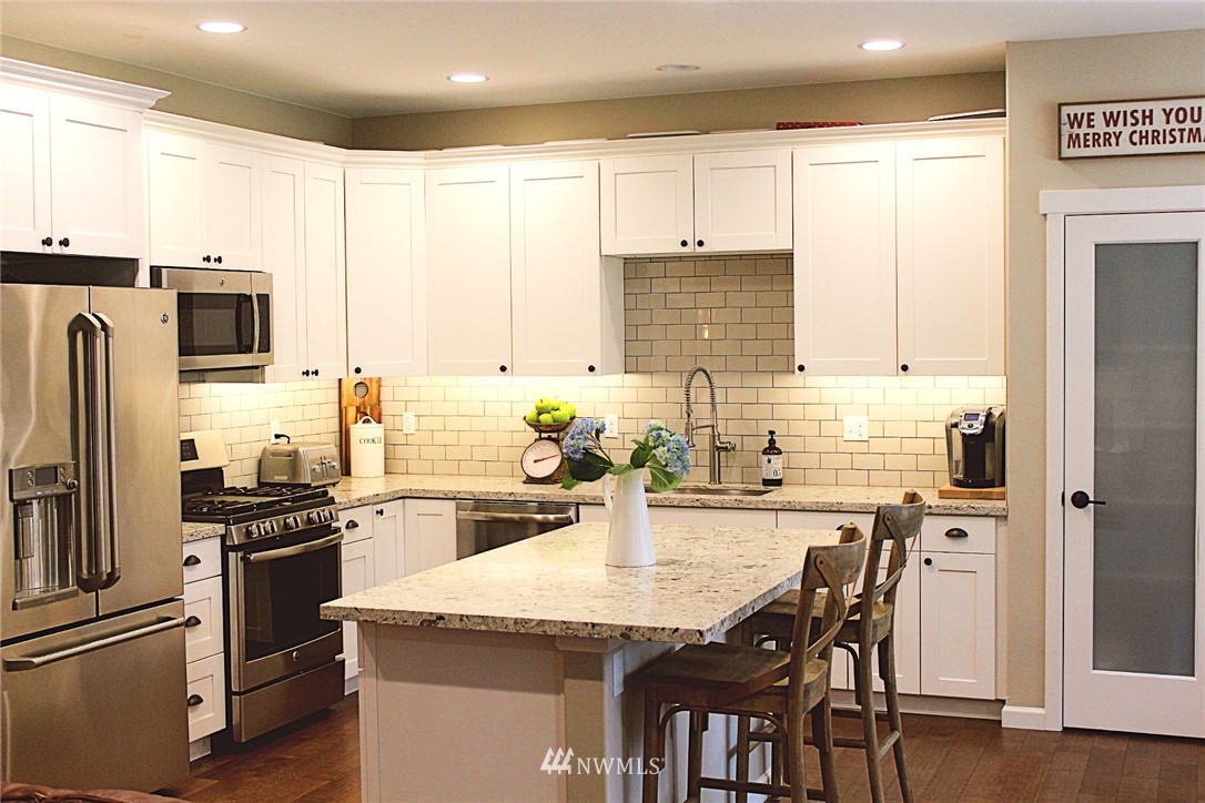 17325 Littlerock Road Southwest Rochester, WA 98579 - Photo 8 of 20 a kitchen with stainless steel appliances granite countertop a kitchen island a stove a refrigerator a sink a dining table and chairs