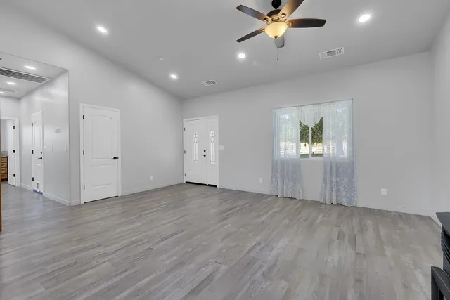 an empty room with a ceiling fan and window