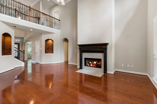 a view of an empty room with wooden floor fireplace and a window