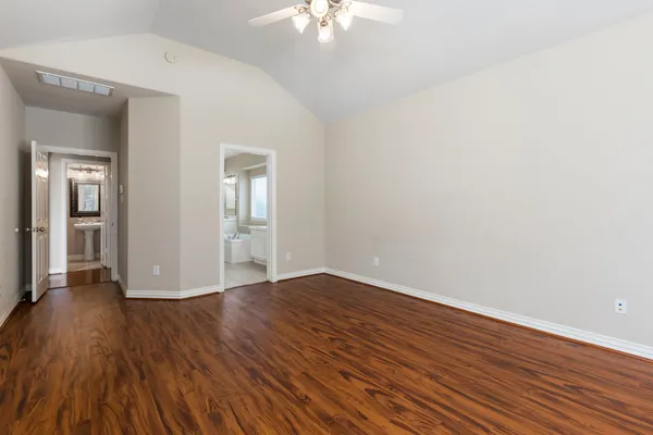 a view of an empty room with wooden floor and a chandelier