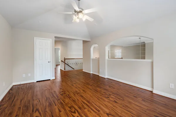 a view of empty room with wooden floor and ceiling fan