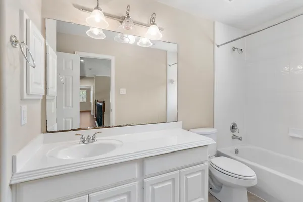 a bathroom with a sink a toilet a mirror a vanity and shower