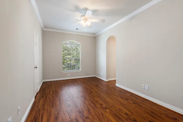 an empty room with wooden floor chandelier fan and windows
