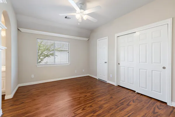an empty room with wooden floor chandelier fan and windows