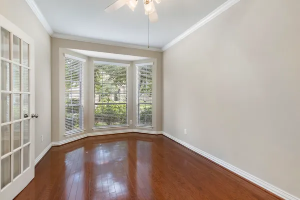 a view of empty room with wooden floor and fan