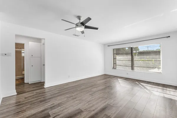 a view of an empty room with wooden floor and a window