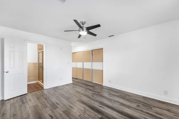 an empty room with wooden floor fan and windows