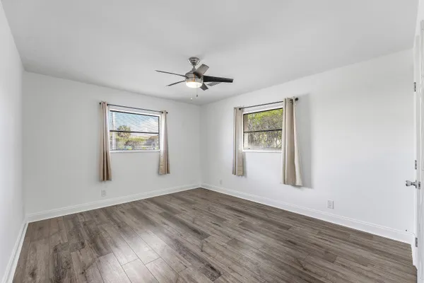 a view of an empty room with a window and wooden floor