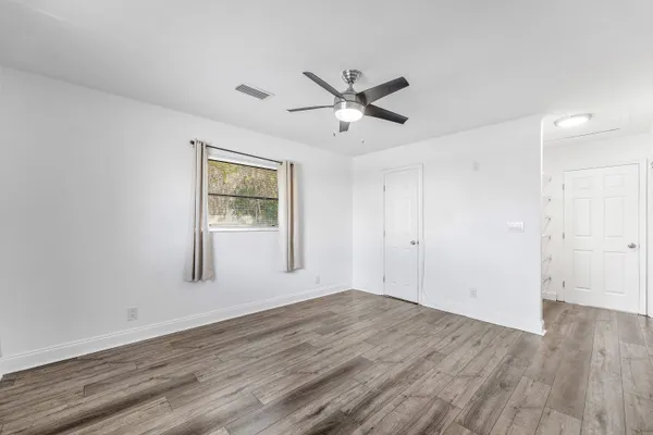a view of empty room with wooden floor and fan