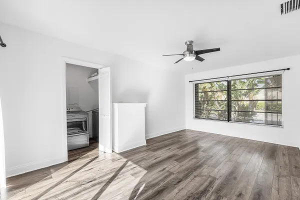a view of an empty room with a window and wooden floor