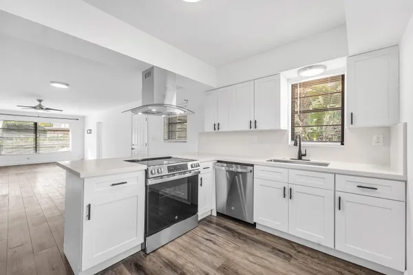 a kitchen with stainless steel appliances granite countertop a stove and white cabinets