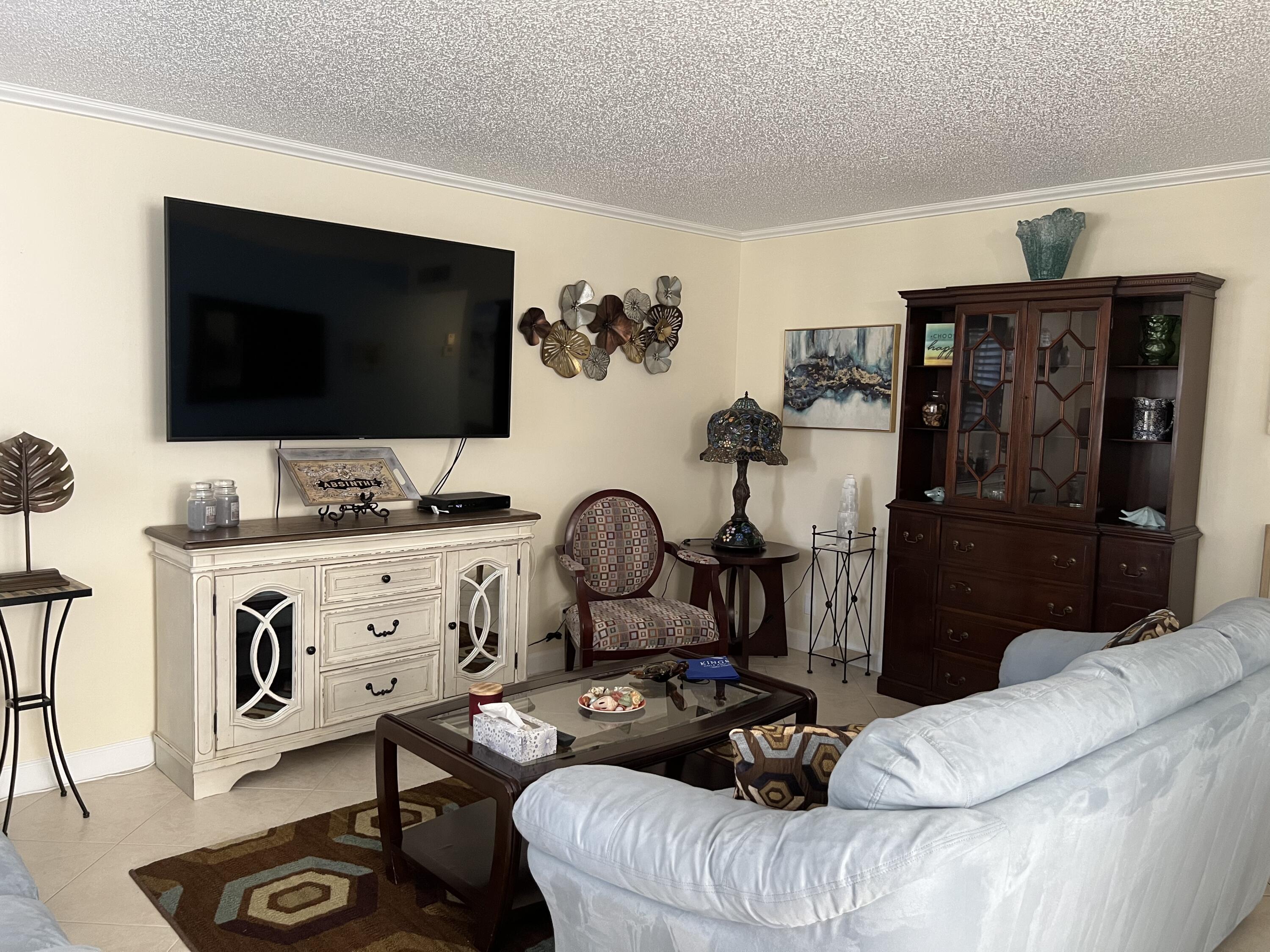 183 Normandy Lane Delray Beach, FL 33484 - Photo 2 of 80 a living room with furniture a flat screen tv and a floor to ceiling window